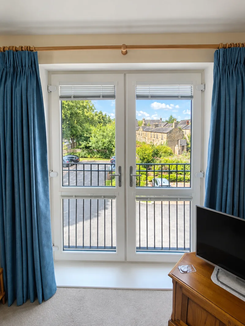 Wooden curtain pole and blue curtains above glazed doors; photo enhanced